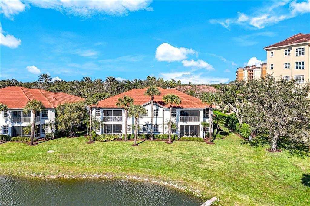 Rear view of property featuring a lawn, a water view, and a balcony