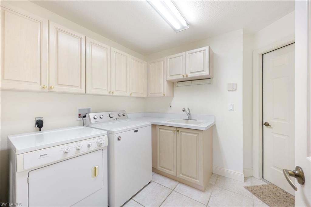 Laundry room with separate washer and dryer, light tile patterned flooring, and cabinet space