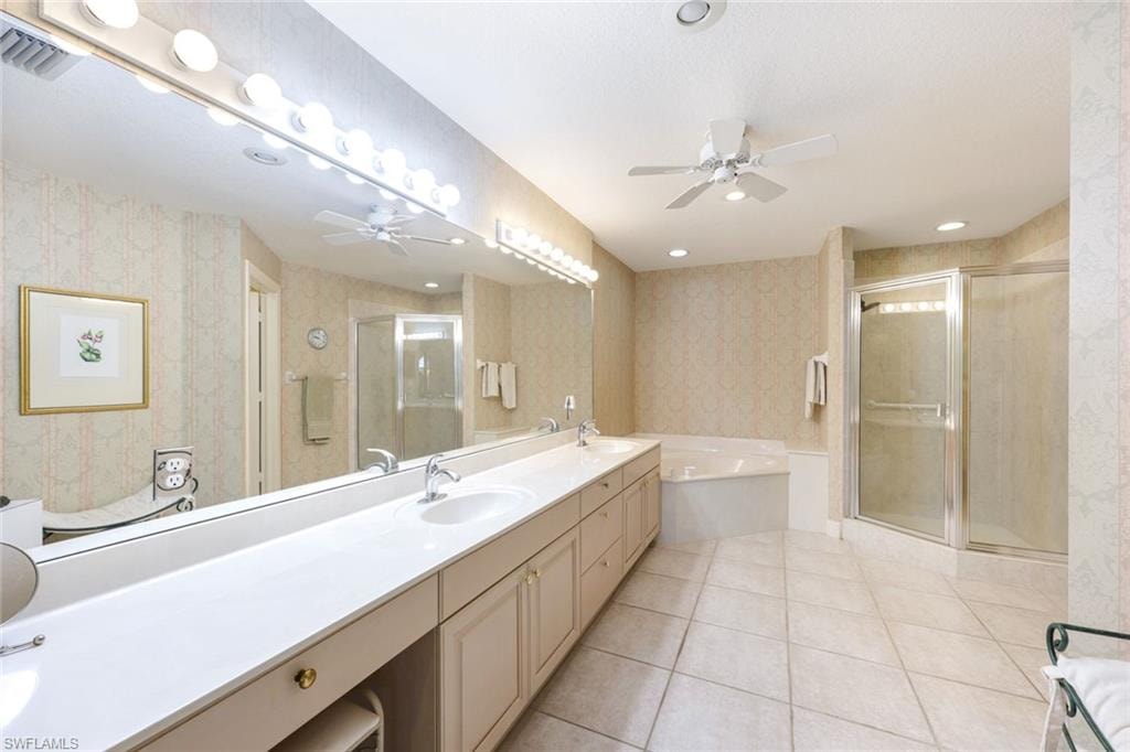Bathroom with a bath, double vanity, a stall shower, a ceiling fan, and light tile patterned floors