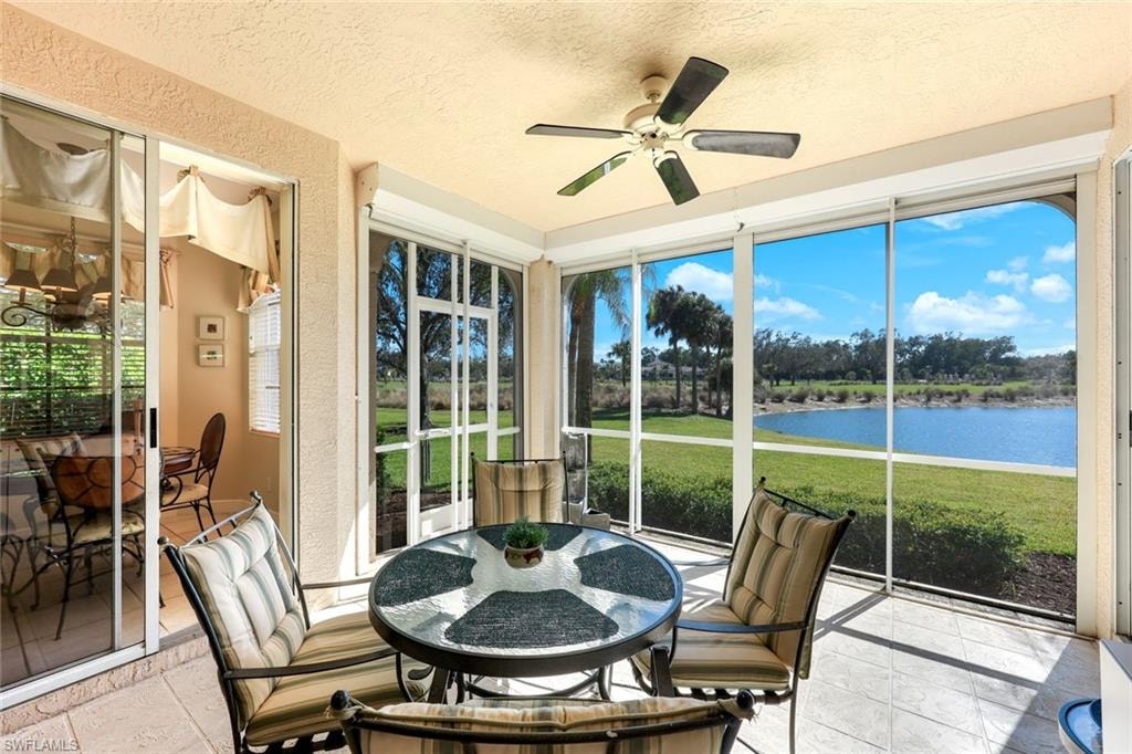 Sunroom with a water view, a textured wall, and a textured ceiling