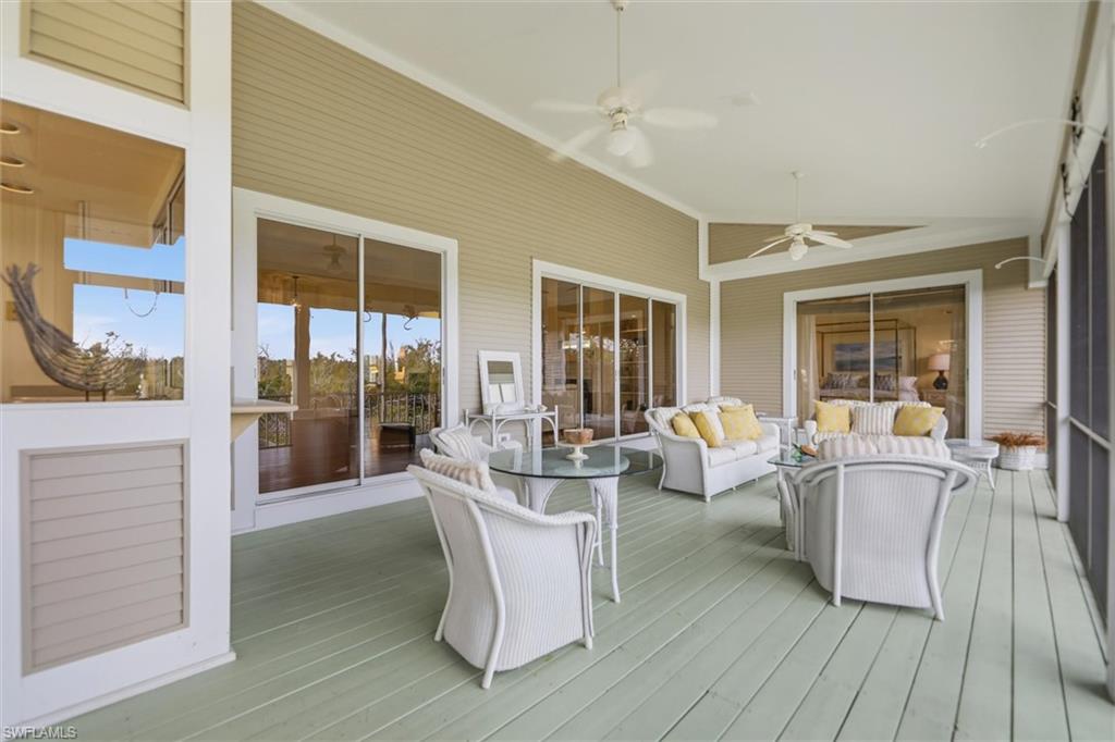 Wooden deck featuring a sunroom, outdoor furniture, and ceiling fan