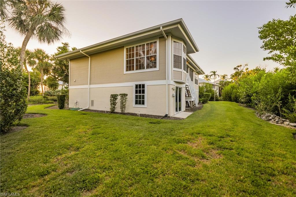 View of property exterior with a lawn and stairs