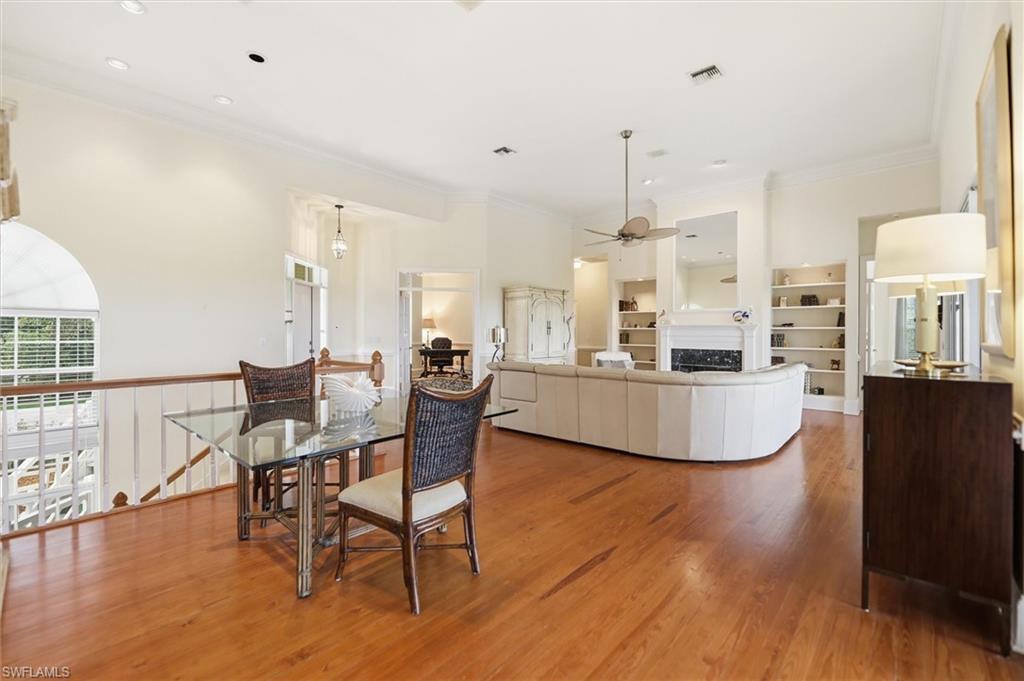 Dining room featuring light wood-style floors, crown molding, a fireplace, and a ceiling fan