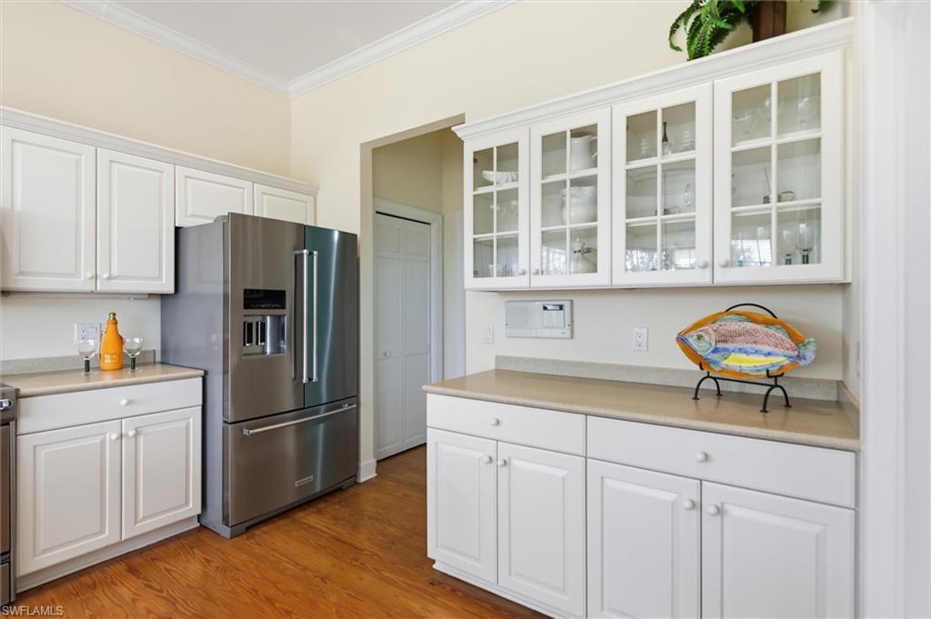 Kitchen featuring white cabinets, high end fridge, glass insert cabinets, light wood-style floors, and ornamental molding