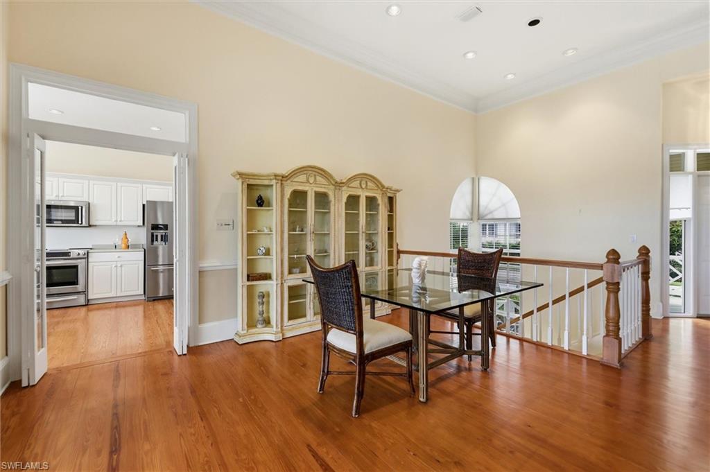 Dining space featuring ornamental molding, light wood-type flooring, recessed lighting, and a high ceiling
