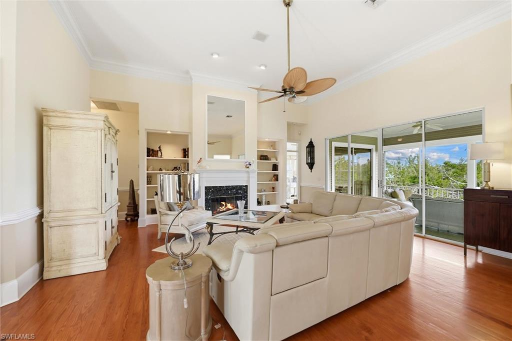 Living area featuring a premium fireplace, crown molding, wood finished floors, and ceiling fan
