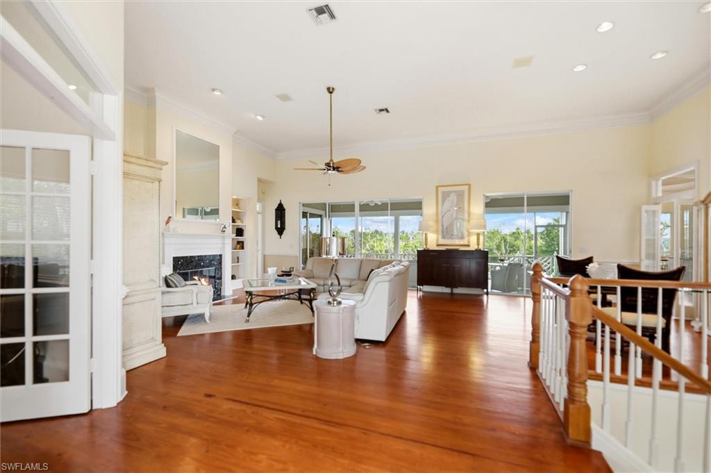 Living room featuring a fireplace, plenty of natural light, ceiling fan, wood finished floors, and ornamental molding