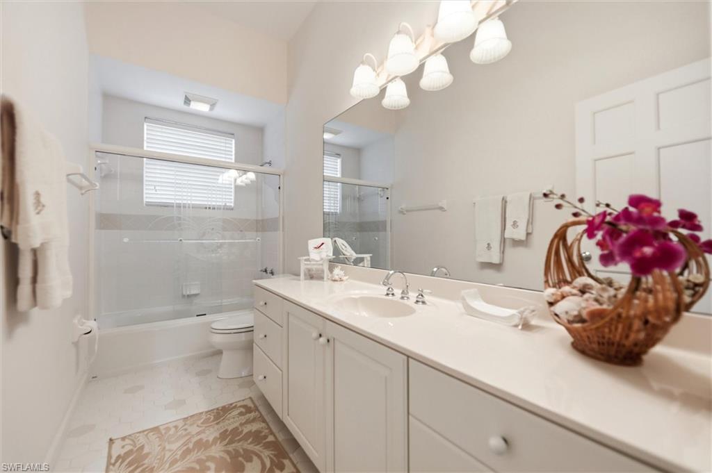 Full bathroom featuring vanity, bath / shower combo with glass door, hanging lights, and light tile patterned floors