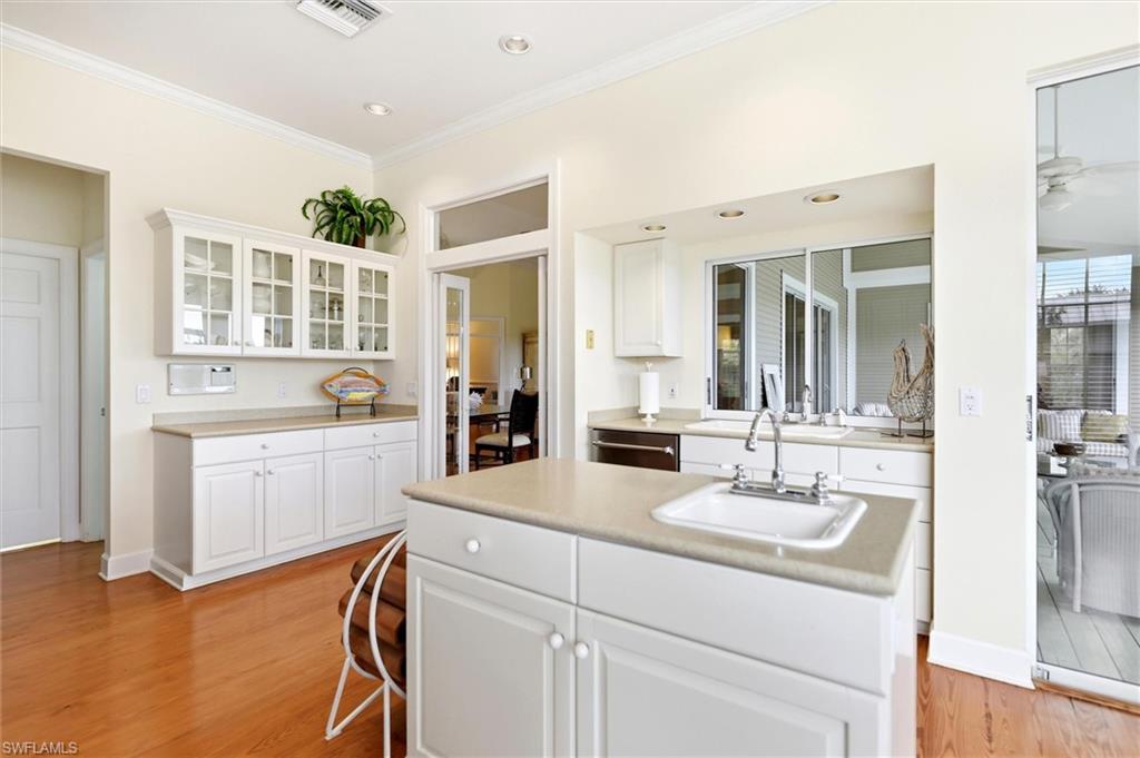 Kitchen featuring white cabinets, glass fronted cabinets, light wood finished floors, light countertops, and a kitchen island