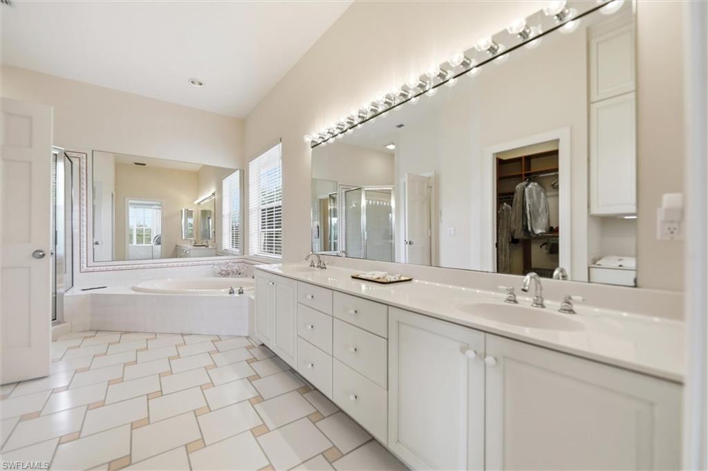 Full bathroom with a garden tub, double vanity, a shower stall, and a walk in closet