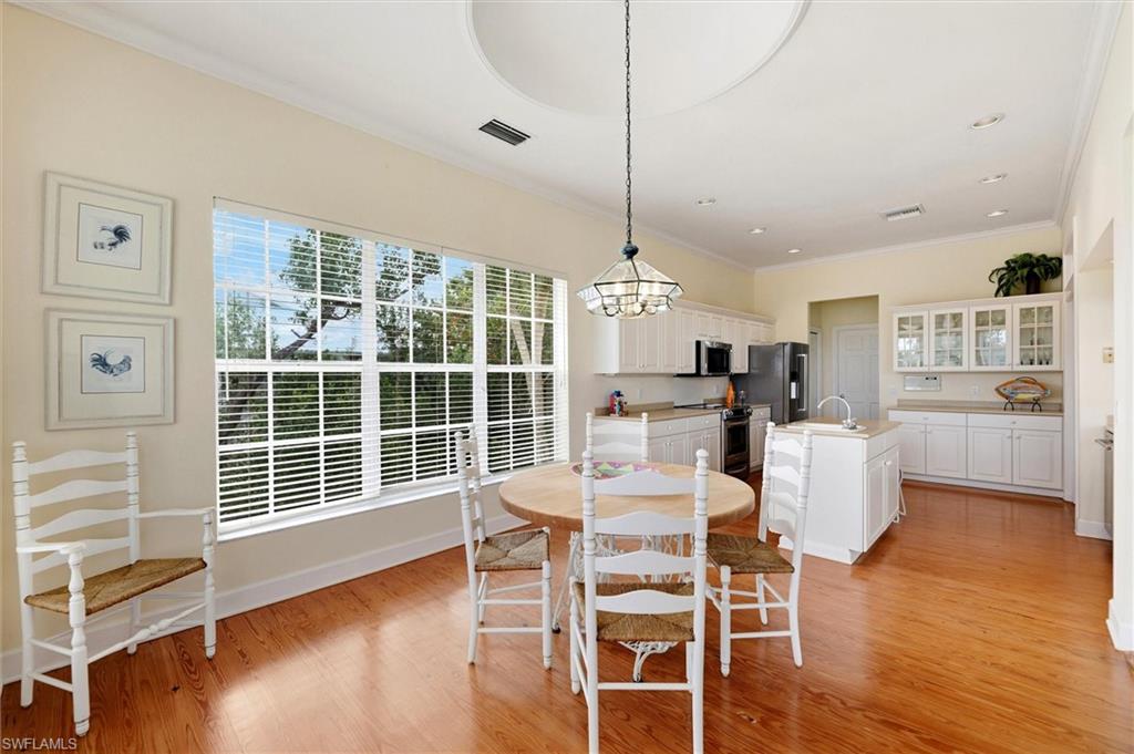 Dining area featuring ornamental molding, light wood-style floors, and suspended lighting