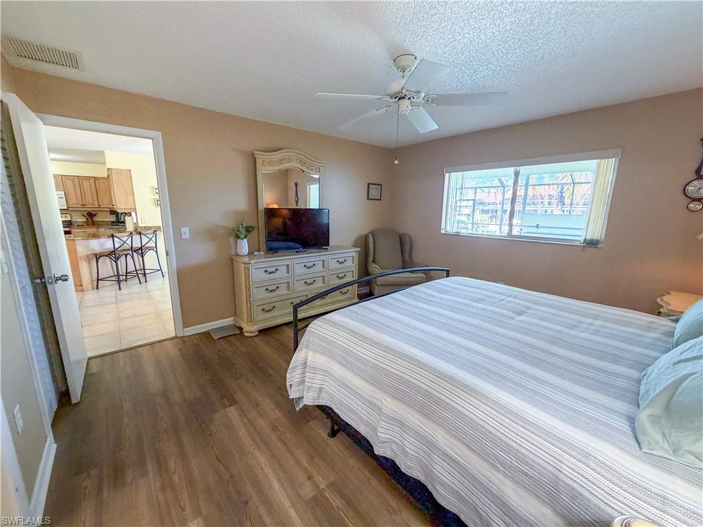 Bedroom featuring dark wood-style floors, a textured ceiling, and a ceiling fan