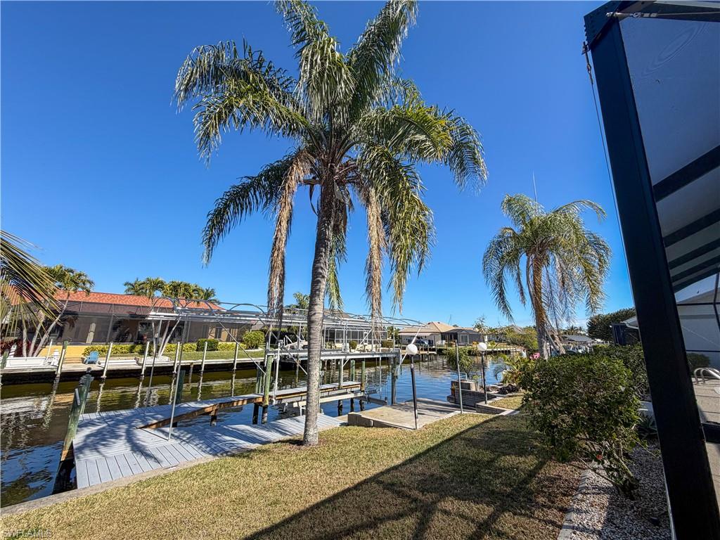 Dock featuring boat lift, a lawn, a residential view, and a water view