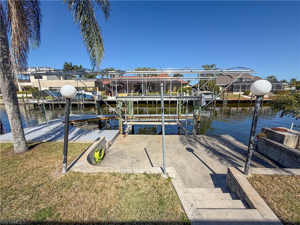 Dock with boat lift, a yard, and a water view