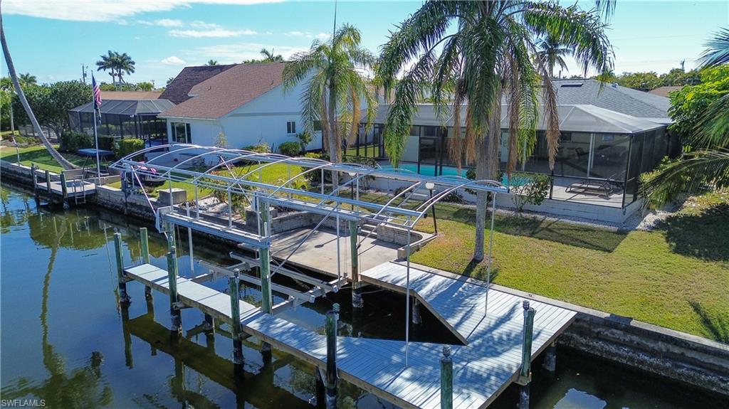 Dock featuring a sunroom, a lanai, a lawn, and a water view