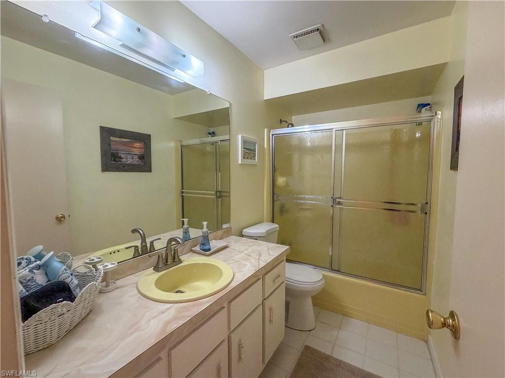 Bathroom with vanity, combined bath / shower with glass door, and light tile patterned floors