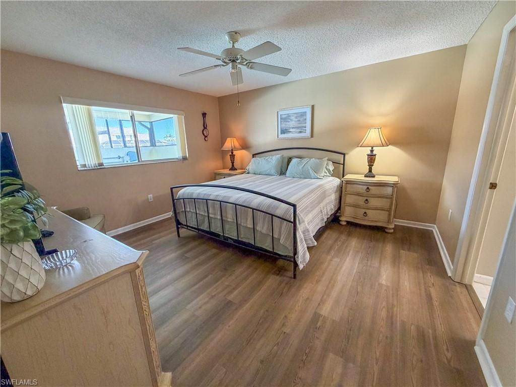 Bedroom with dark wood-style floors, a textured ceiling, and a ceiling fan