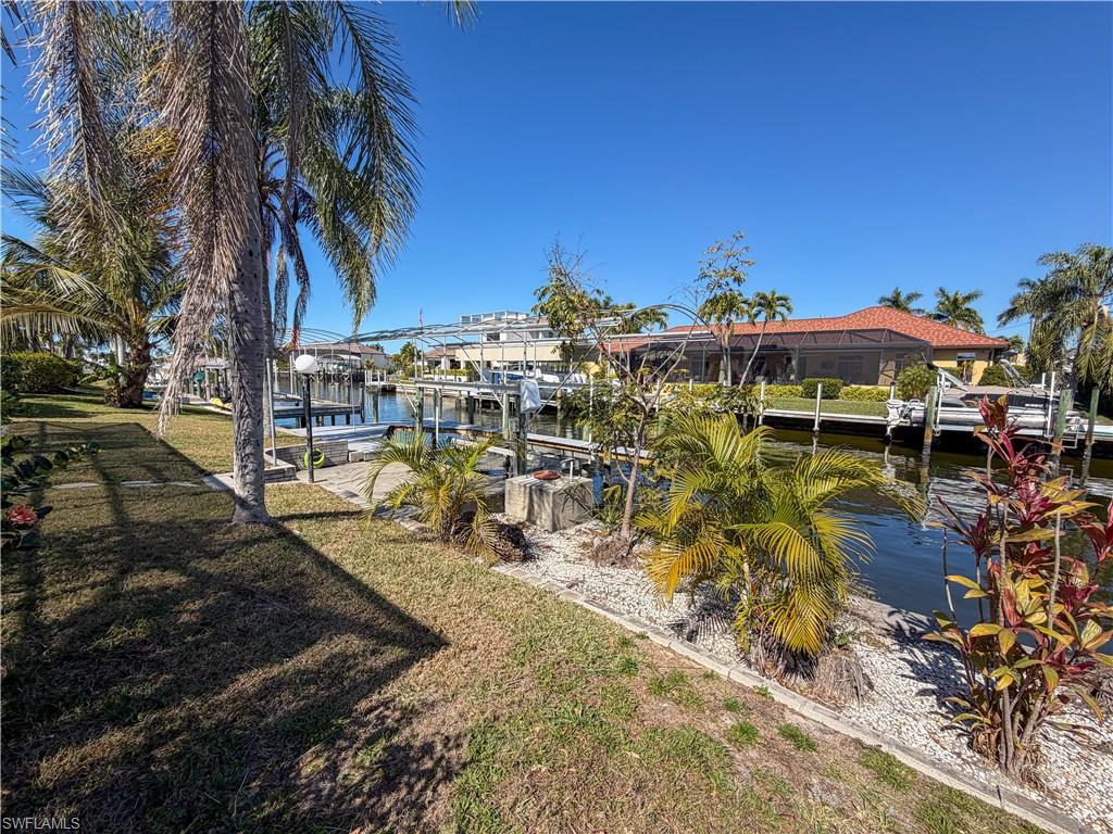 Dock area featuring a lawn, boat lift, and a water view