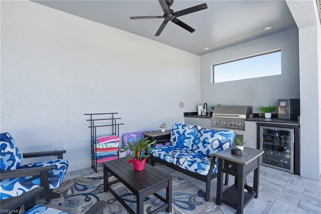 View of patio with an outdoor kitchen and area to lounge, beverage cooler, and ceiling fan