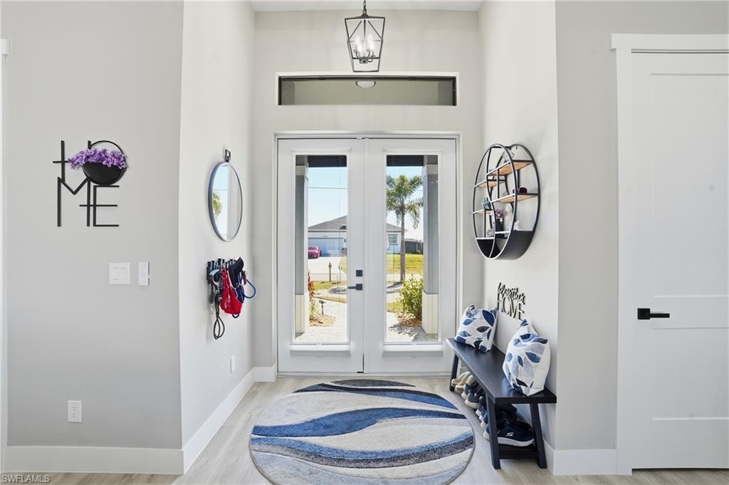 Entrance foyer featuring french doors, a chandelier, and light wood finished floors