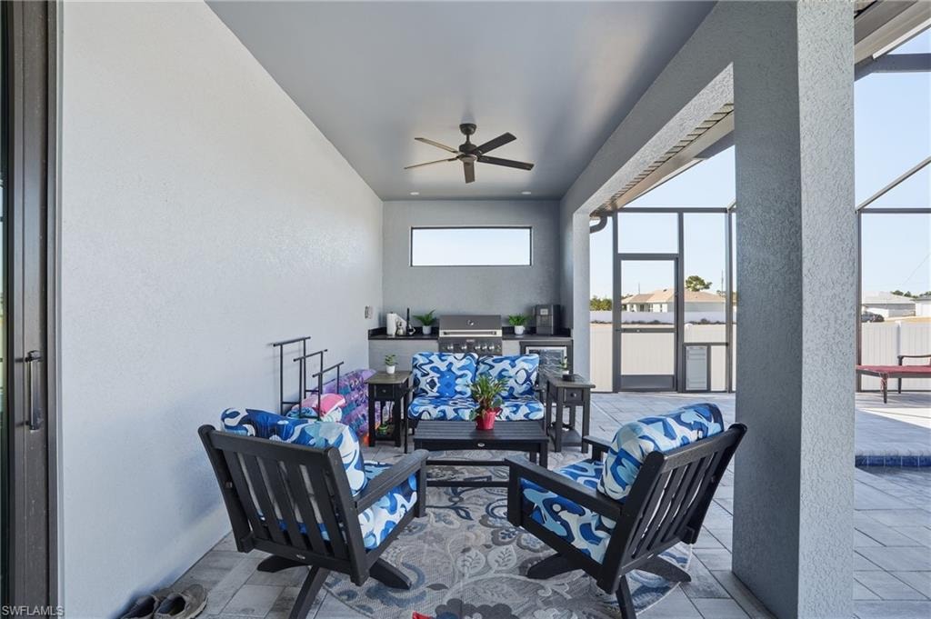 View of patio / terrace with glass enclosure, ceiling fan, a sunroom, and an outdoor kitchen and area to lounge