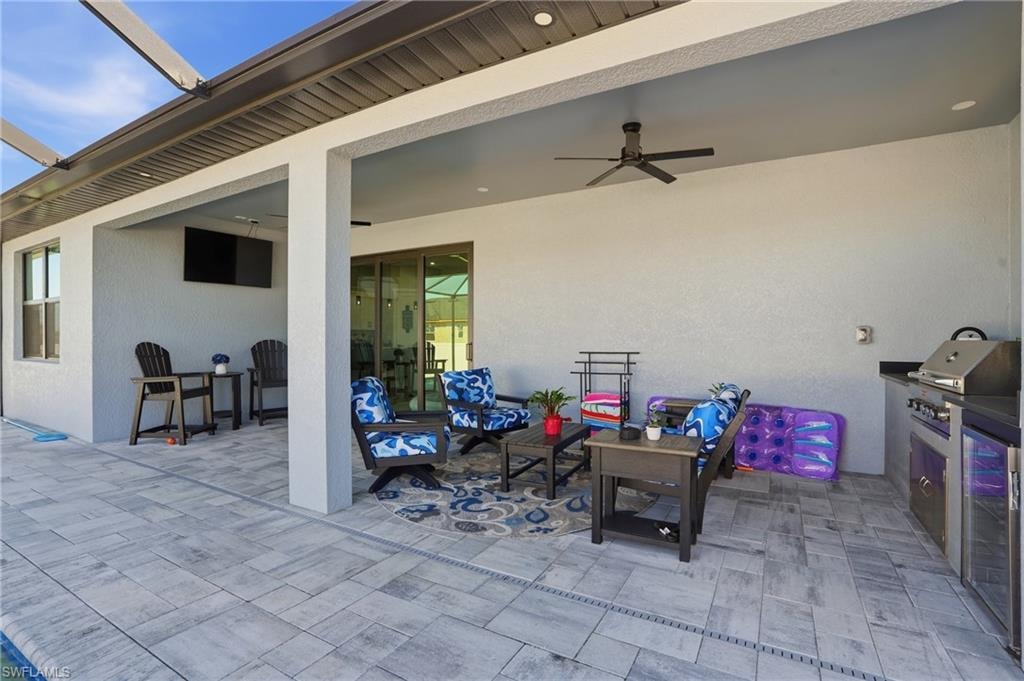 View of patio with ceiling fan, a grill, and glass enclosure