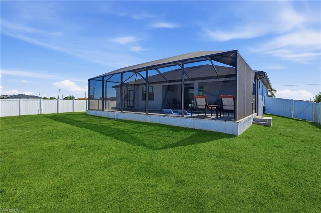 Back of house featuring a fenced backyard, glass enclosure, a sunroom, and a gate
