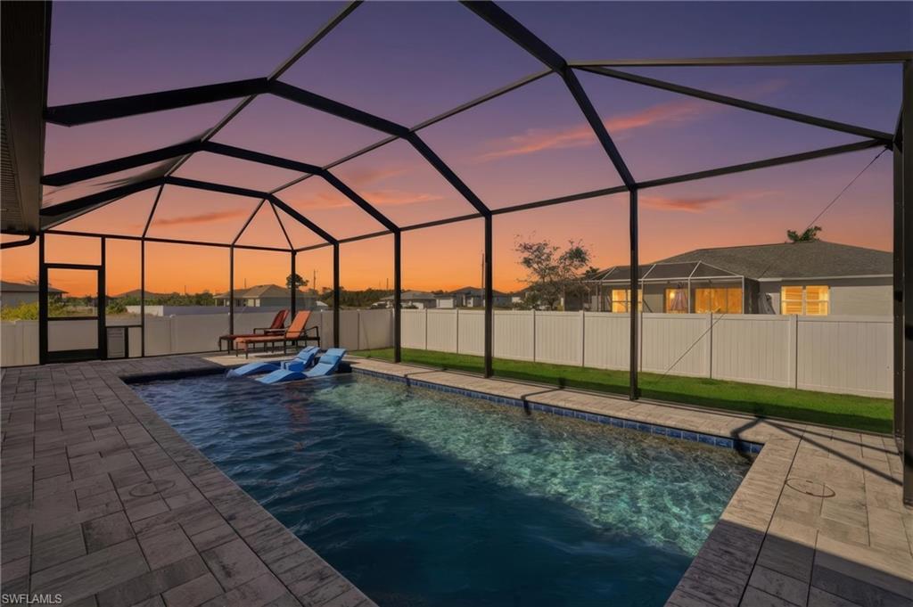 Pool at dusk with a sunroom and a lanai