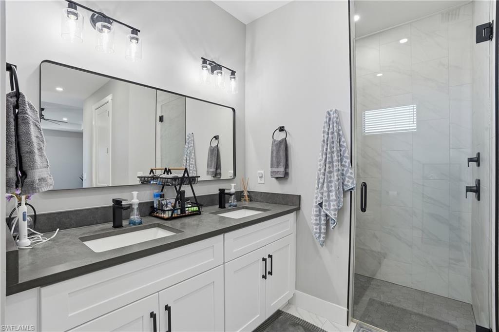Bathroom with double vanity, a stall shower, and recessed lighting