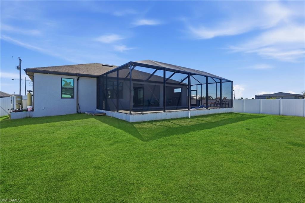 Rear view of house featuring glass enclosure, a sunroom, and stucco siding