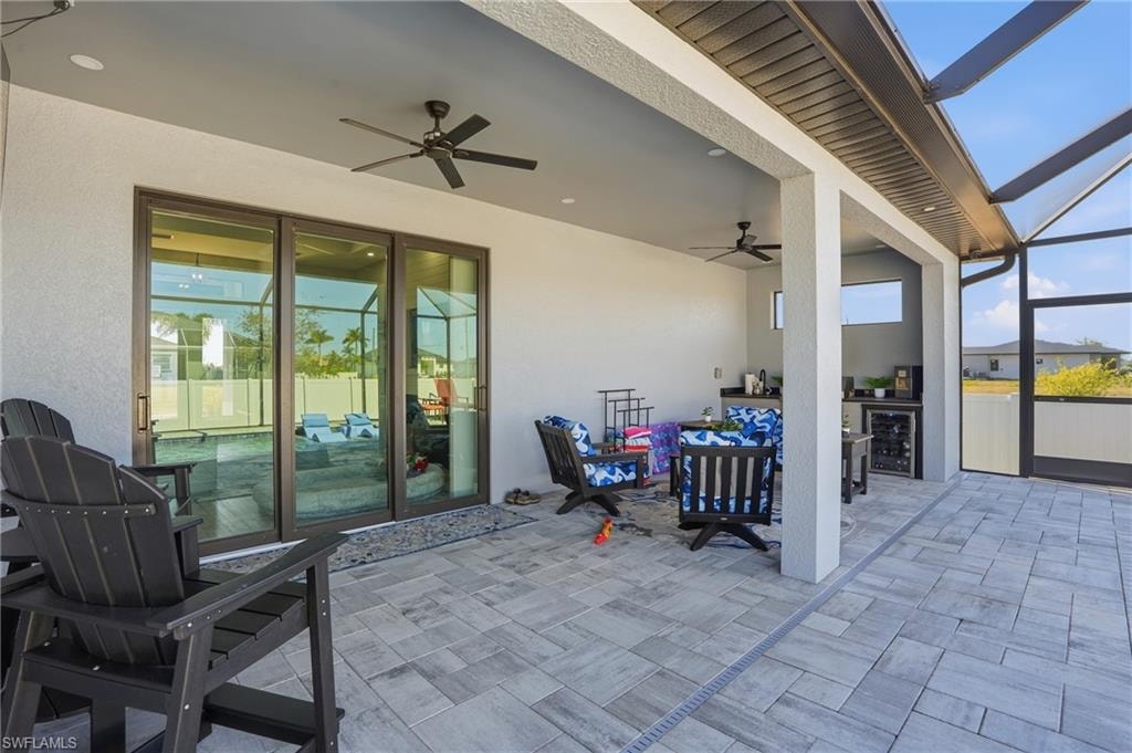 View of patio / terrace featuring ceiling fan, a sunroom, a lanai, beverage cooler, and exterior kitchen
