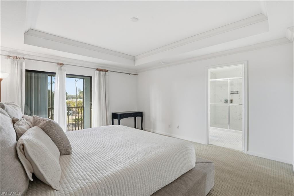 Carpeted bedroom featuring access to outside, a tray ceiling, connected bathroom, and crown molding