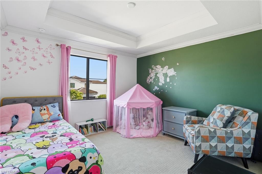 Bedroom with light carpet, ornamental molding, and a crib