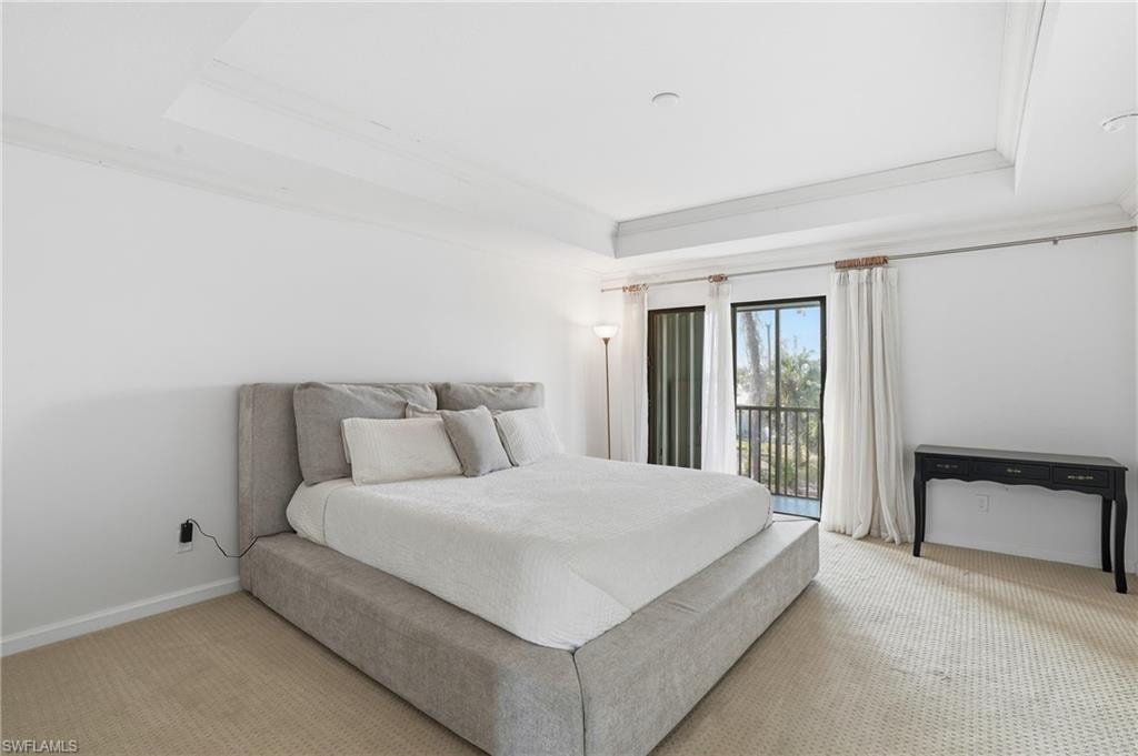 Bedroom featuring access to outside, carpet flooring, a tray ceiling, and crown molding