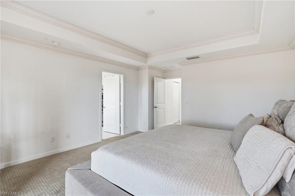 Bedroom with carpet floors, a raised ceiling, and ornamental molding