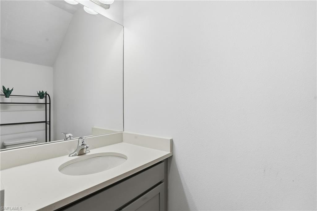 Half bath featuring vanity and vaulted ceiling