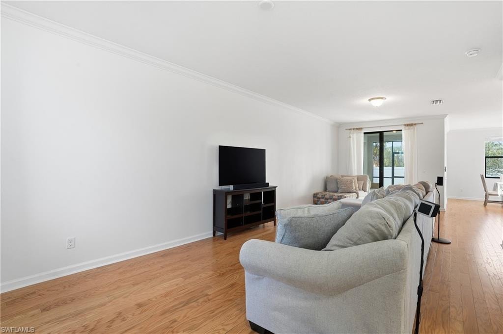 Living room with light wood-type flooring and crown molding