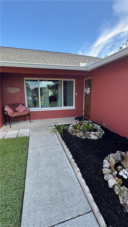 Property entrance with a shingled roof and stucco siding