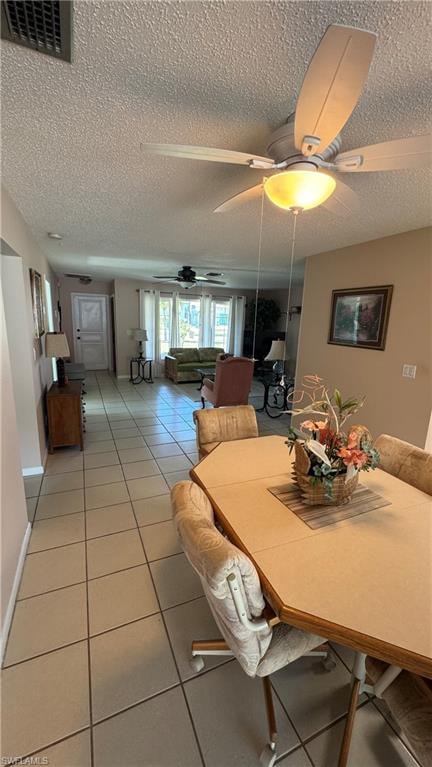 Dining space with a textured ceiling, light tile patterned floors, and ceiling fan