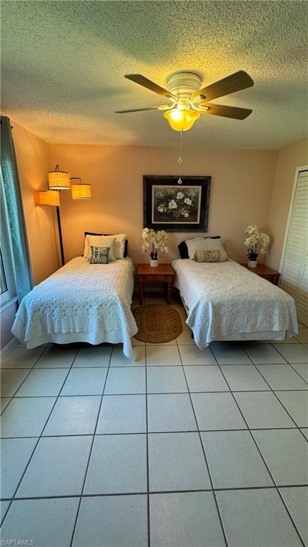 Bedroom with light tile patterned flooring, a ceiling fan, a textured ceiling, and a closet