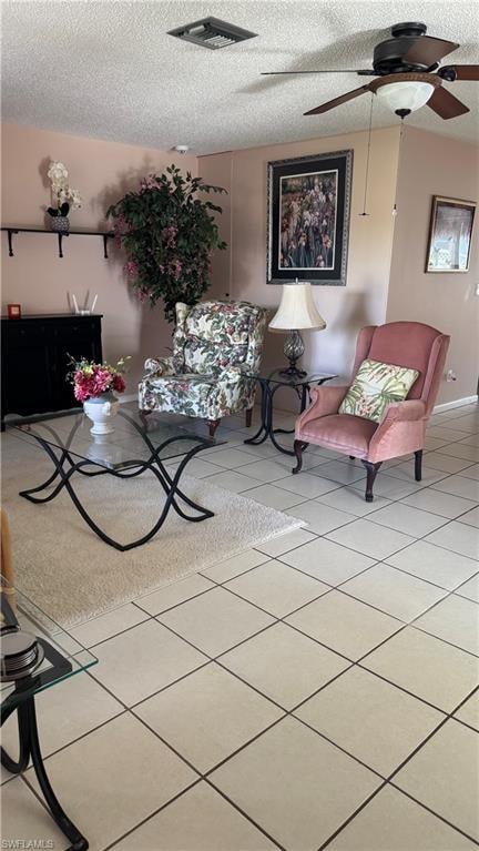 Living area with a textured ceiling, ceiling fan, and light tile patterned floors