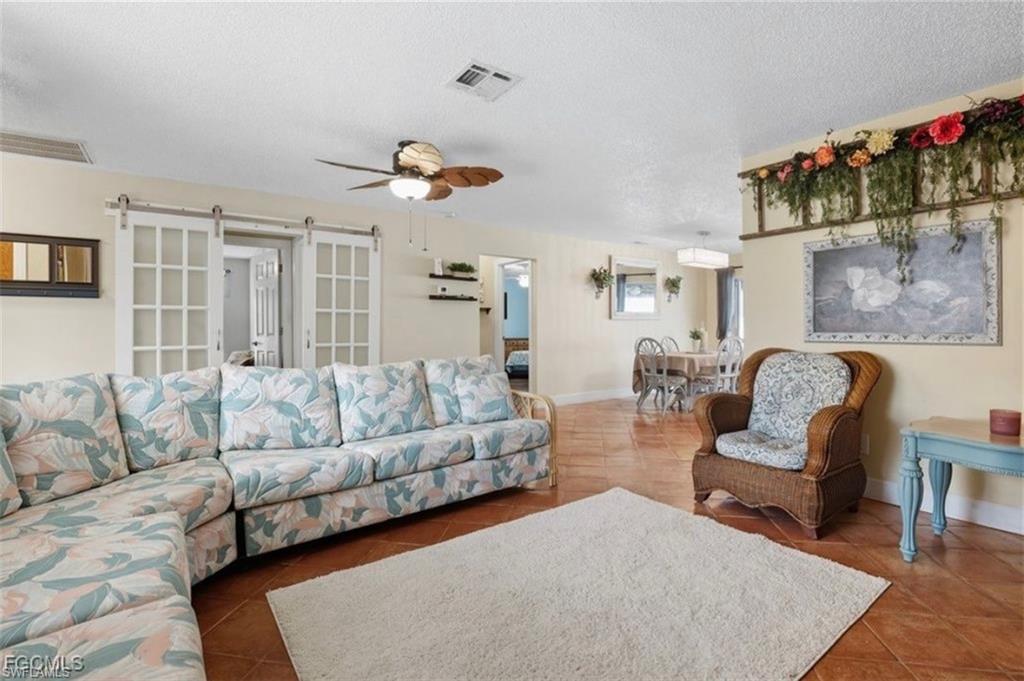 Living room featuring a ceiling fan, a barn door, and a textured ceiling