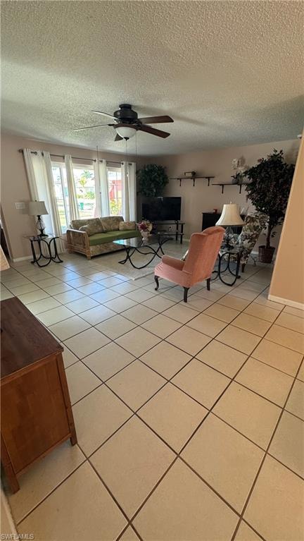 Living room with ceiling fan, a textured ceiling, and light tile patterned floors