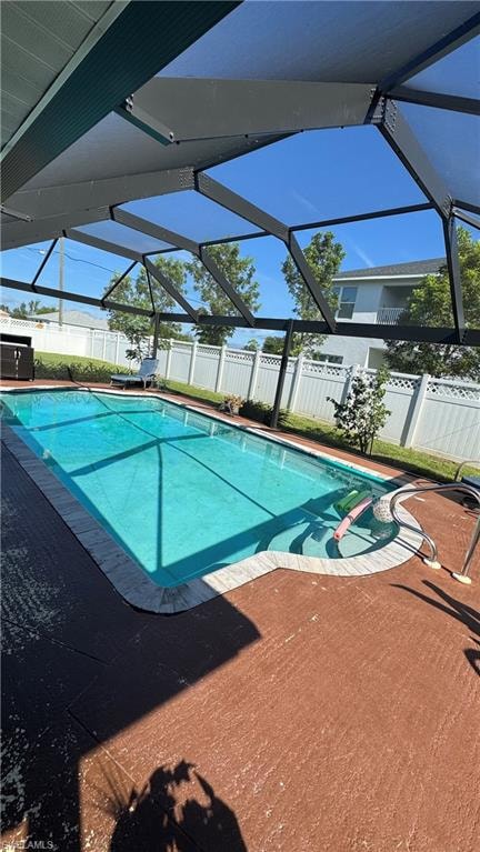 View of pool featuring a lanai, a sunroom, a fenced backyard, and patio surround
