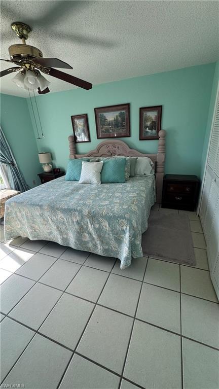 Tiled bedroom featuring a textured ceiling, ceiling fan, and a closet