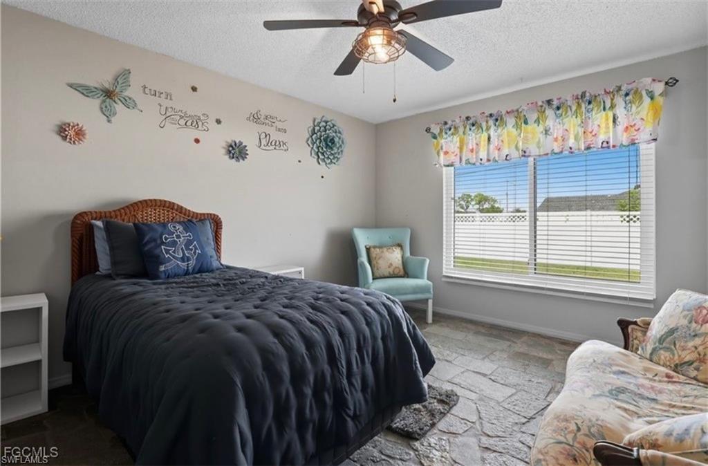 Bedroom featuring stone finish flooring, a textured ceiling, and ceiling fan