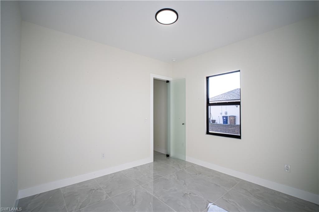 Unfurnished room featuring baseboards and light marble finish flooring