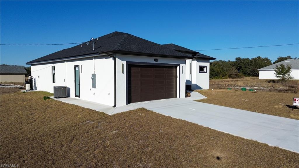 View of property exterior featuring a shingled roof, stucco siding, concrete driveway, and an attached garage