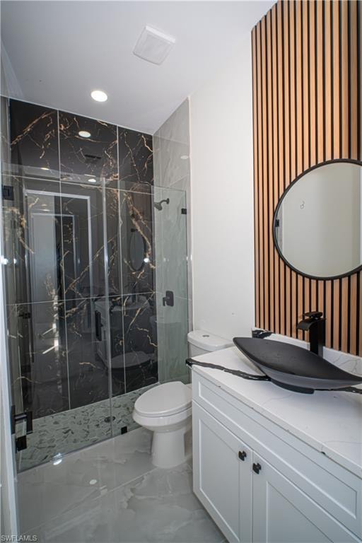 Full bath with vanity, a marble finish shower, recessed lighting, and light marble finish floors