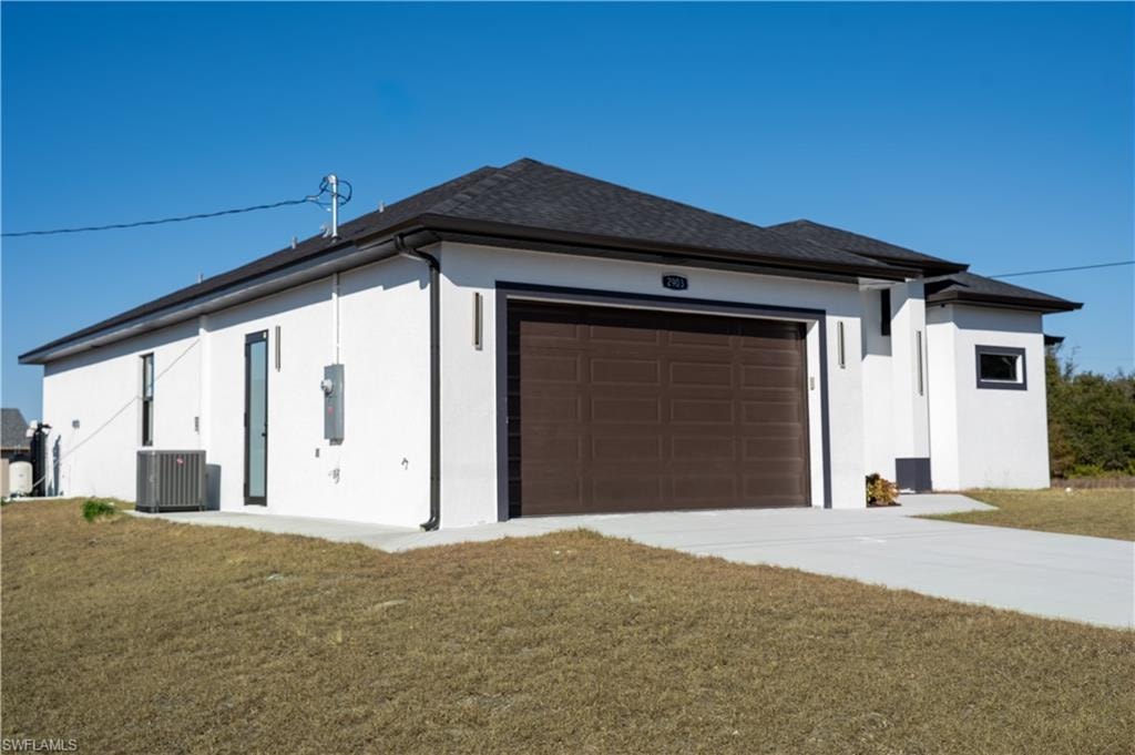 View of side of home with stucco siding, a lawn, and a garage